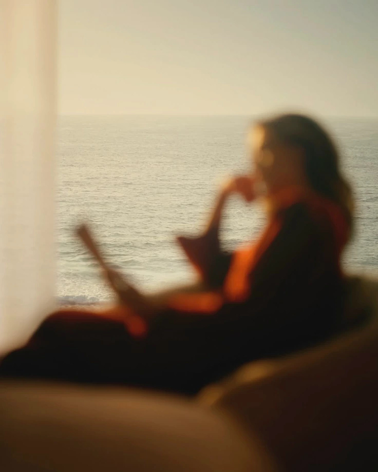 Mulher sentada em desfoque suave observando o mar ao amanhecer
